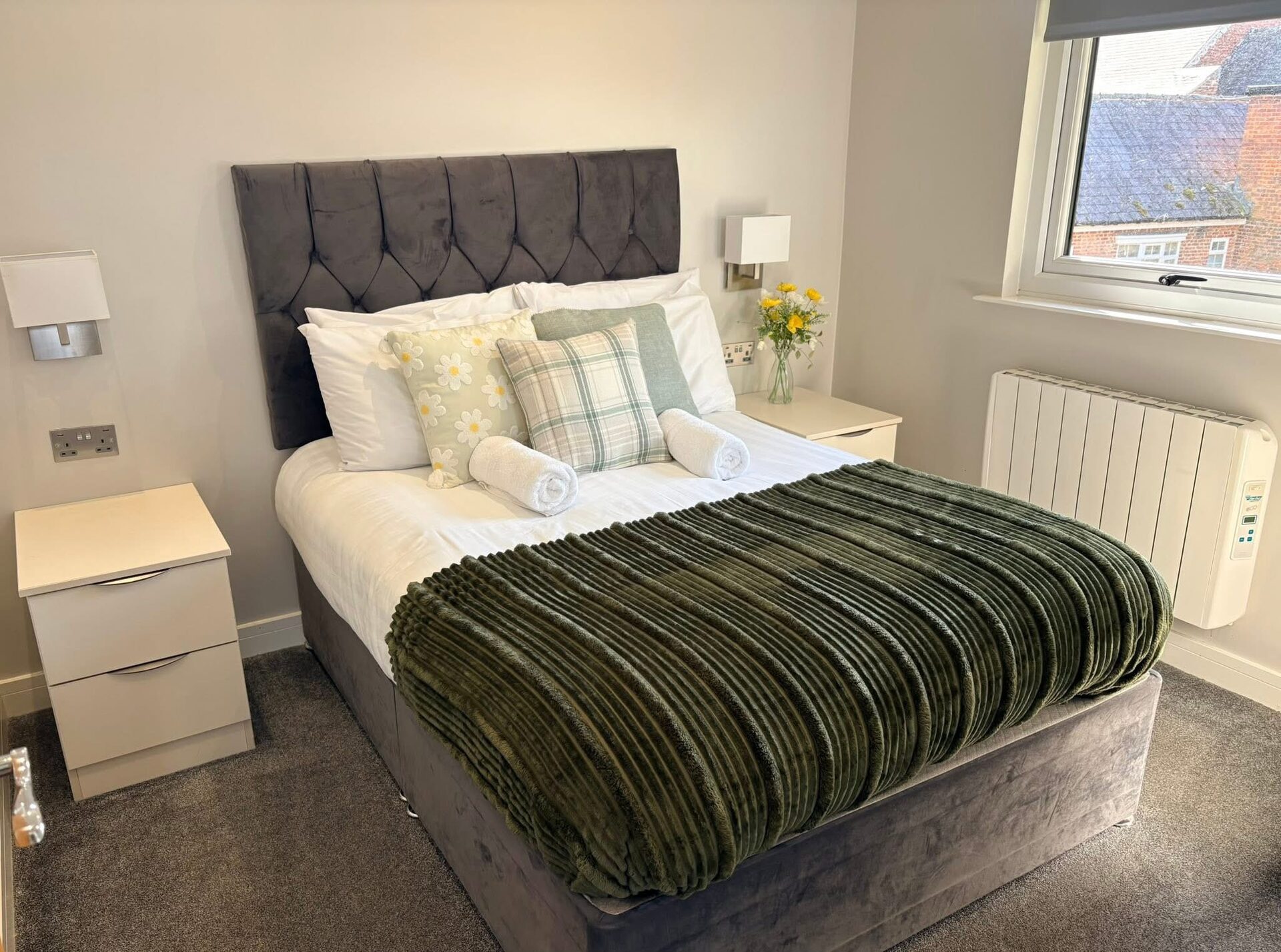 Double bedroom with green throw and plaid cushions