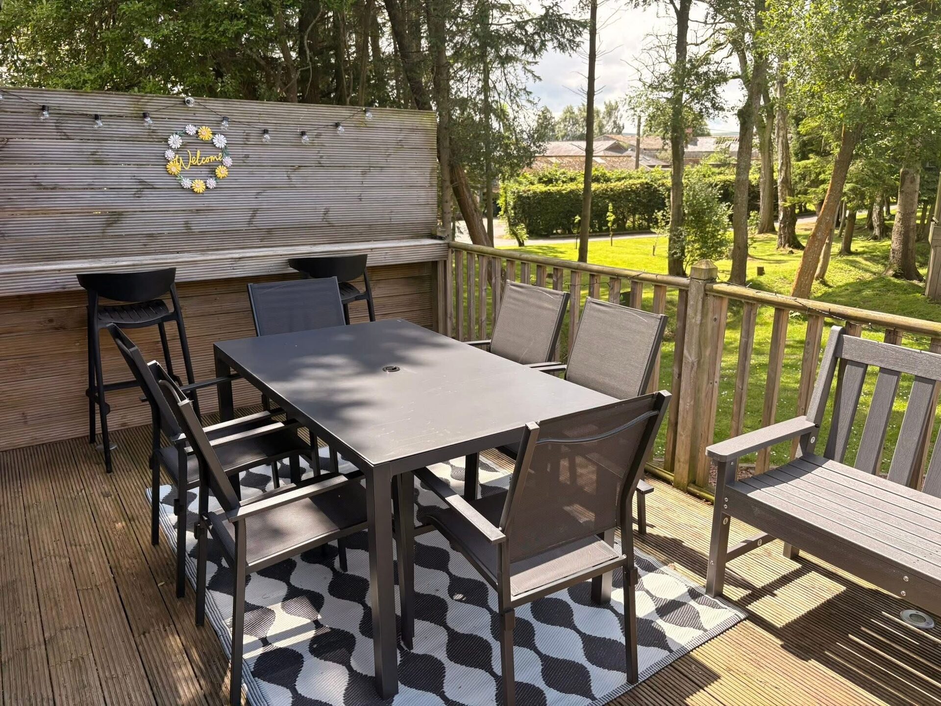 Outdoor dining table on the lodge decking, looking out over trees and lawn